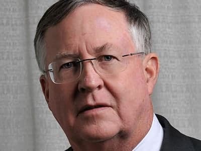 Portrait of Dr. James Elsey, Treasurer of Friends of Fisher House Charleston, wearing wire-rimmed glasses and a dark suit