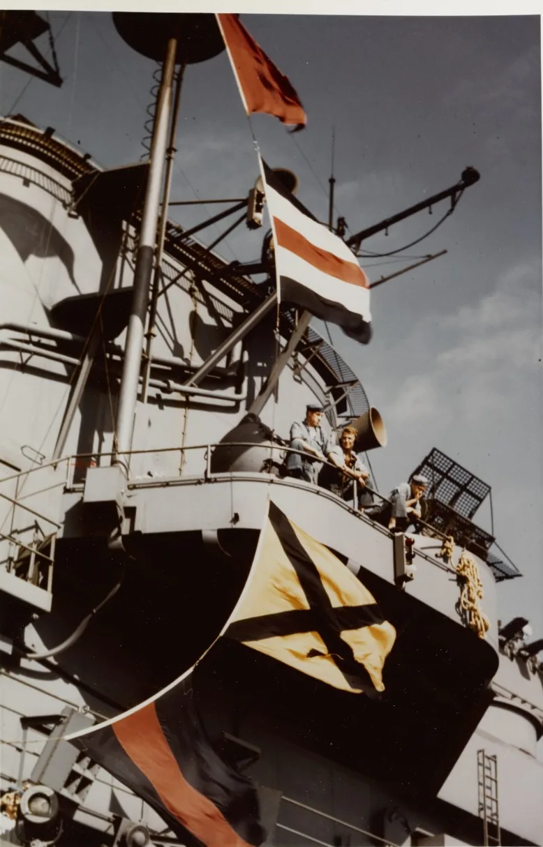 A family walking the pier toward the USS Yorktown at Patriots Point, American flags flying alongside