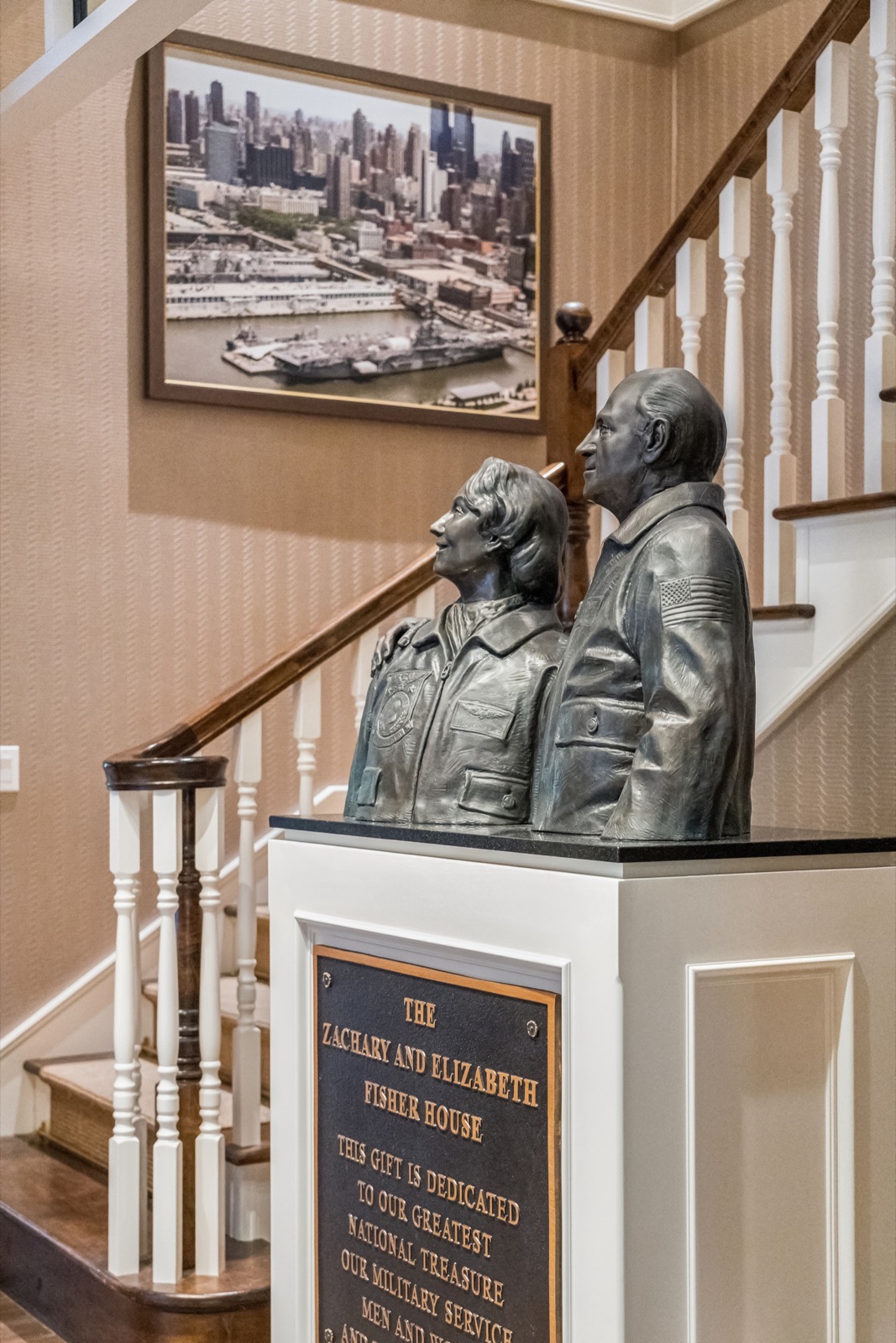 Bronze busts of Zachary and Elizabeth Fisher on a pedestal with a dedication plaque, beside the staircase in the Charleston Fisher House